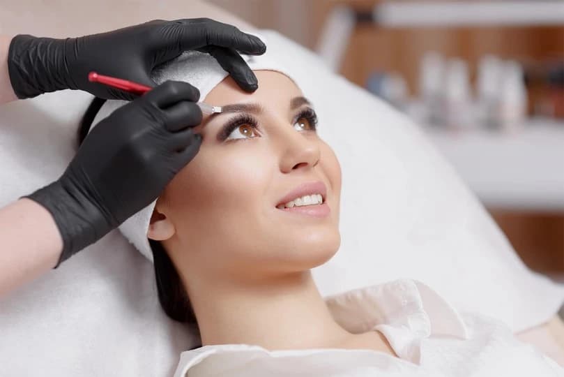 young woman smiling while microblading eyebrows
